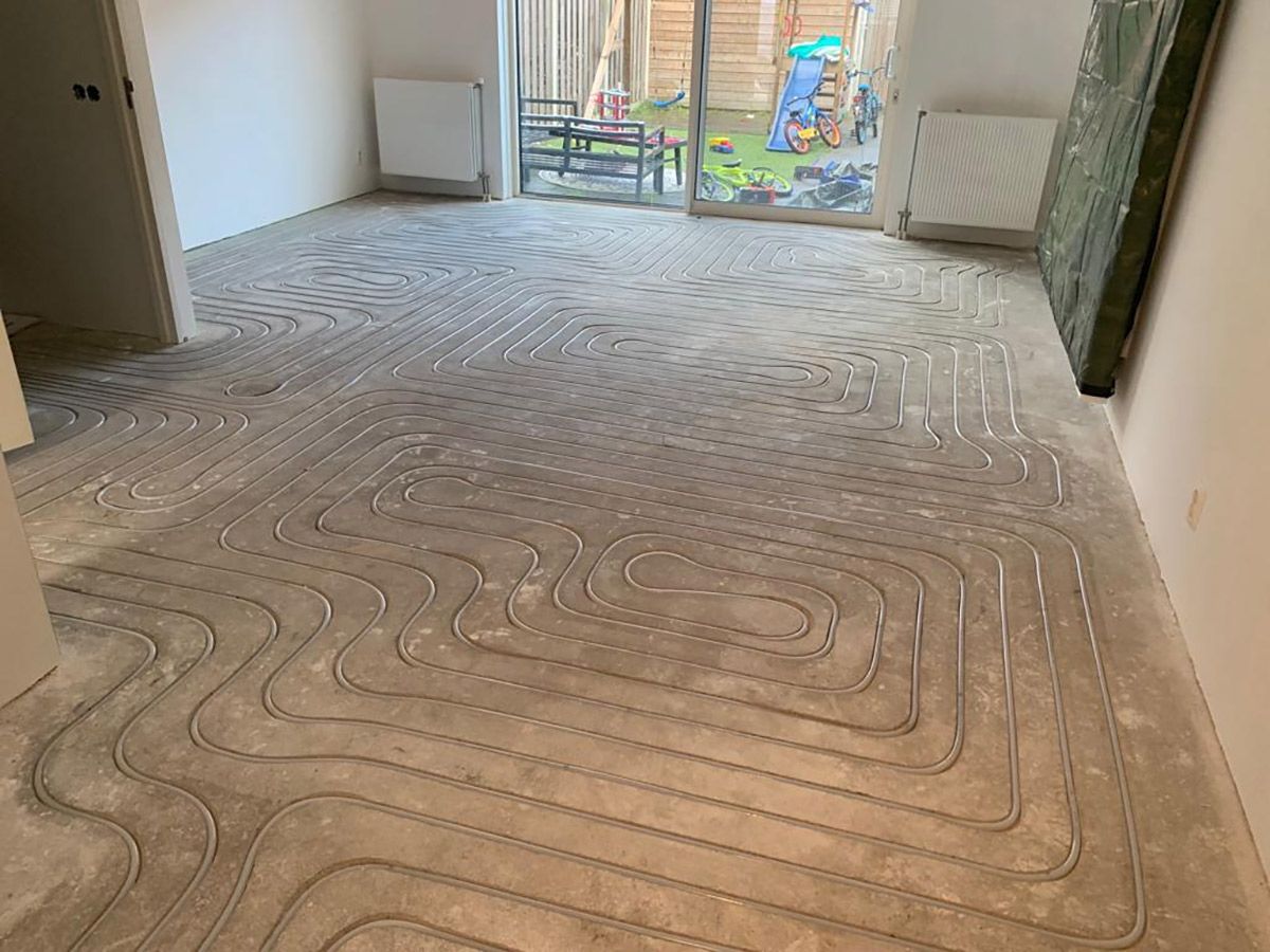 Ingefreesde vloerverwarming: leidingen liggen in de sleuven van de cementdekvloer, klaar voor de gietvloer