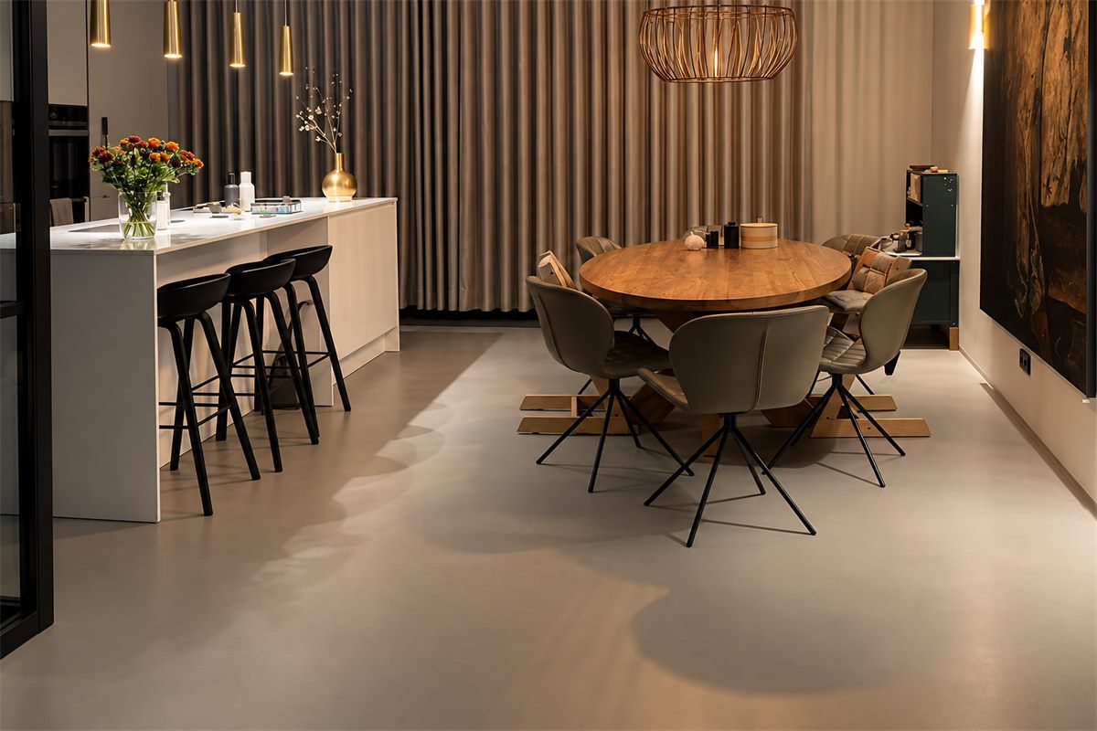 Gietvloer in een luxe keuken in Hilversum Taupe gietvloer in een luxe keuken met eethoek en gouden hanglampen in Hilversum